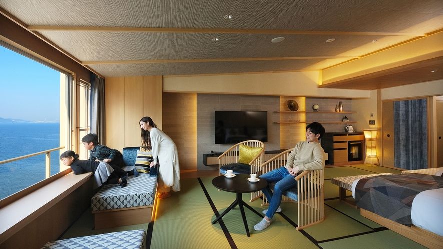 鴎風亭の窓から海が見える部屋で家族４人がくつろぐ様子